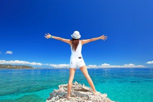 海に向かって大きく手を広げる女性